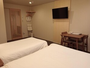 A hotel room with two single beds, a wooden desk, a flat-screen TV mounted on the wall, and a wooden wardrobe. - HIZ Hotel Gion-shirakawa (Kyoto)