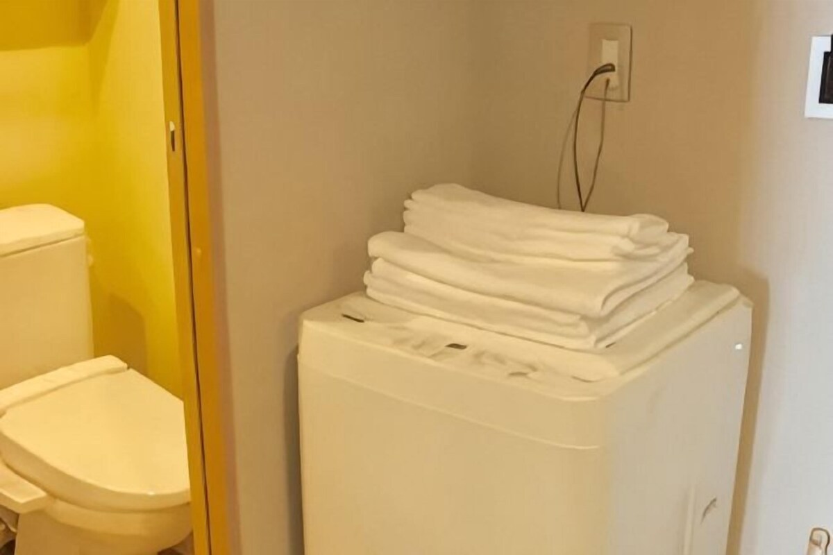 Eine weiße Waschmaschine, gestapelt mit weißen Handtüchern in einem Badezimmer.