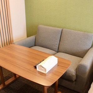Una habitación con una mesa de madera y un sofá gris.