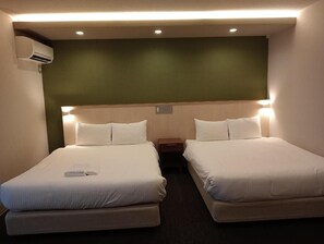 A hotel room with two beds, a nightstand, and an air conditioning unit.