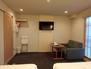 Ett hotellrum med en säng, en soffa, en tv, ett litet bord och ett fönster.