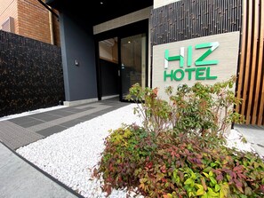 A hotel entrance with a sign reading 'HIZ HOTEL' and a small garden area with plants. - HIZ Hotel Gion-shirakawa (Kyoto)