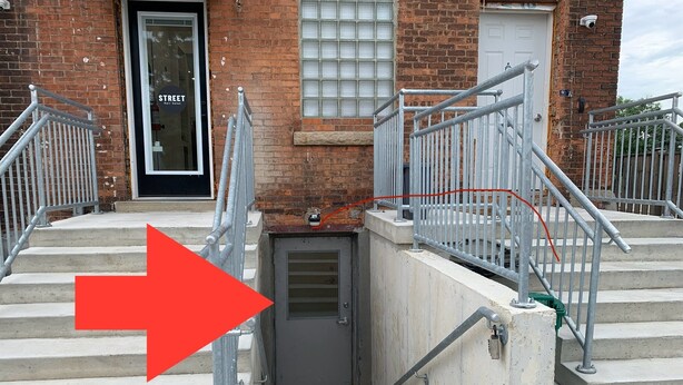 A building entrance with a metal staircase and a door marked "STREET."