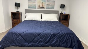 A bedroom with a large bed, two bedside tables, and three wall-mounted paintings.