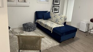 A modern living room with a blue sofa, a patterned throw, and a wicker chair.