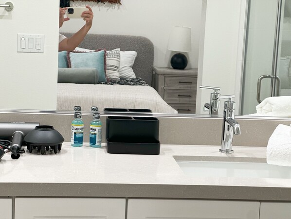 A bathroom with a sink, mirror, and toiletries.