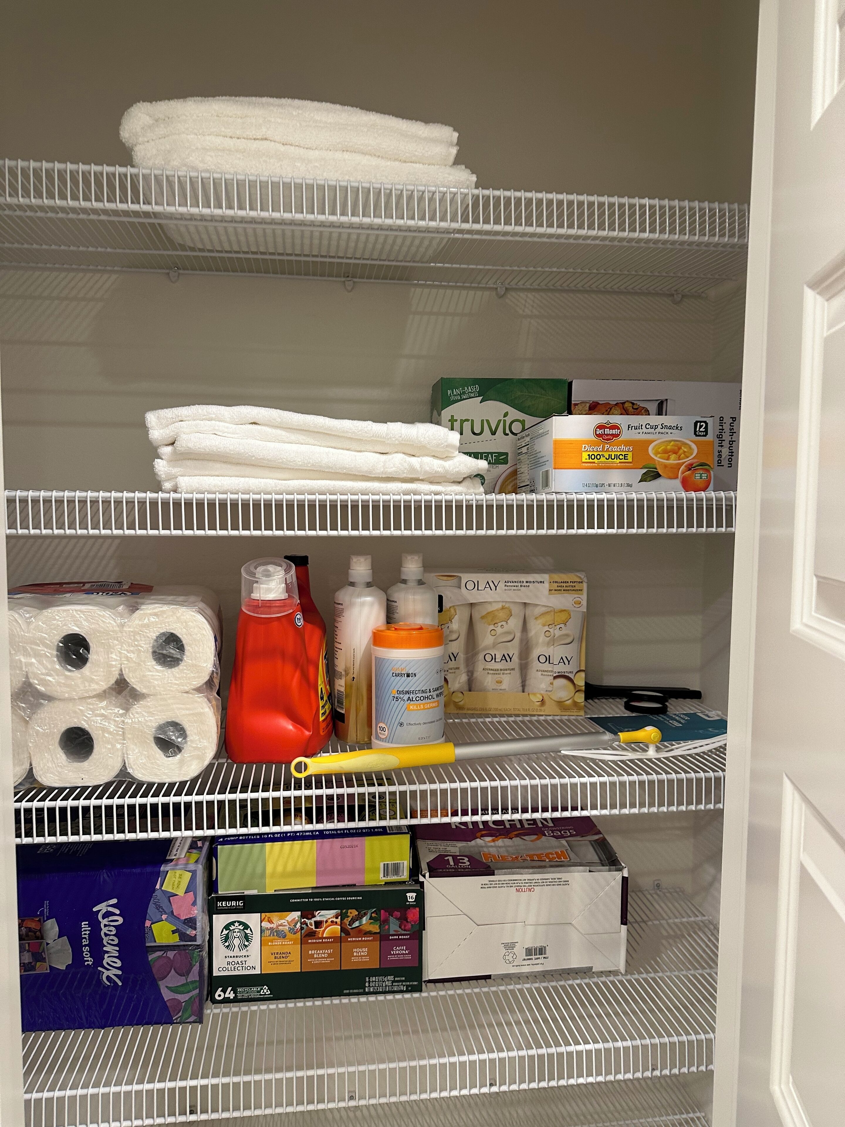 A storage area with shelves containing towels, cleaning supplies, and packaged food items.