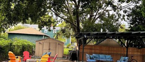 A backyard with outdoor seating, a barbecue area, and a covered patio.