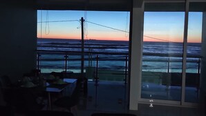 Habitació amb vista a l'oceà al capvespre, una taula de dinar i un llibre.