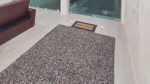 Un interior modern amb una paret de vidre que ofereix vista a l'oceà, un sofà vermell i una catifa de benvinguda.