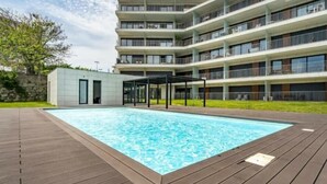 A modern multi-story building with a swimming pool and a covered outdoor seating area.