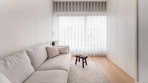 A minimalist living room with a sofa, a small table, and sheer curtains.