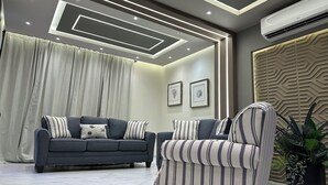 Una sala moderna con un sofá gris, un sillón a rayas y una planta en maceta.