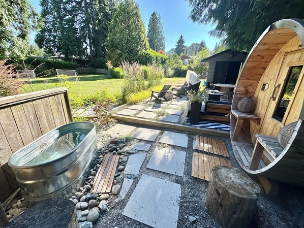 A wooden deck with a hot tub, seating area, and a small wooden structure.