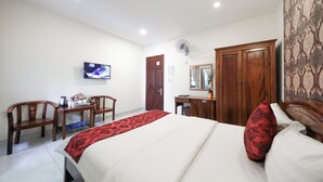 Ett hotellrum med en säng, ett skrivbord, en stol, en tv och en garderob.