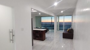 A spacious living area with a kitchen, a sofa, and a view of the sunset. - Luxury Front View Beach House 3-bedroom with WiFi in Playas de Rosarito and more (Playas de Rosarito)