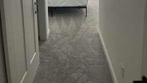 Quarto com cama, ventoinha no teto e janela com cortinas.