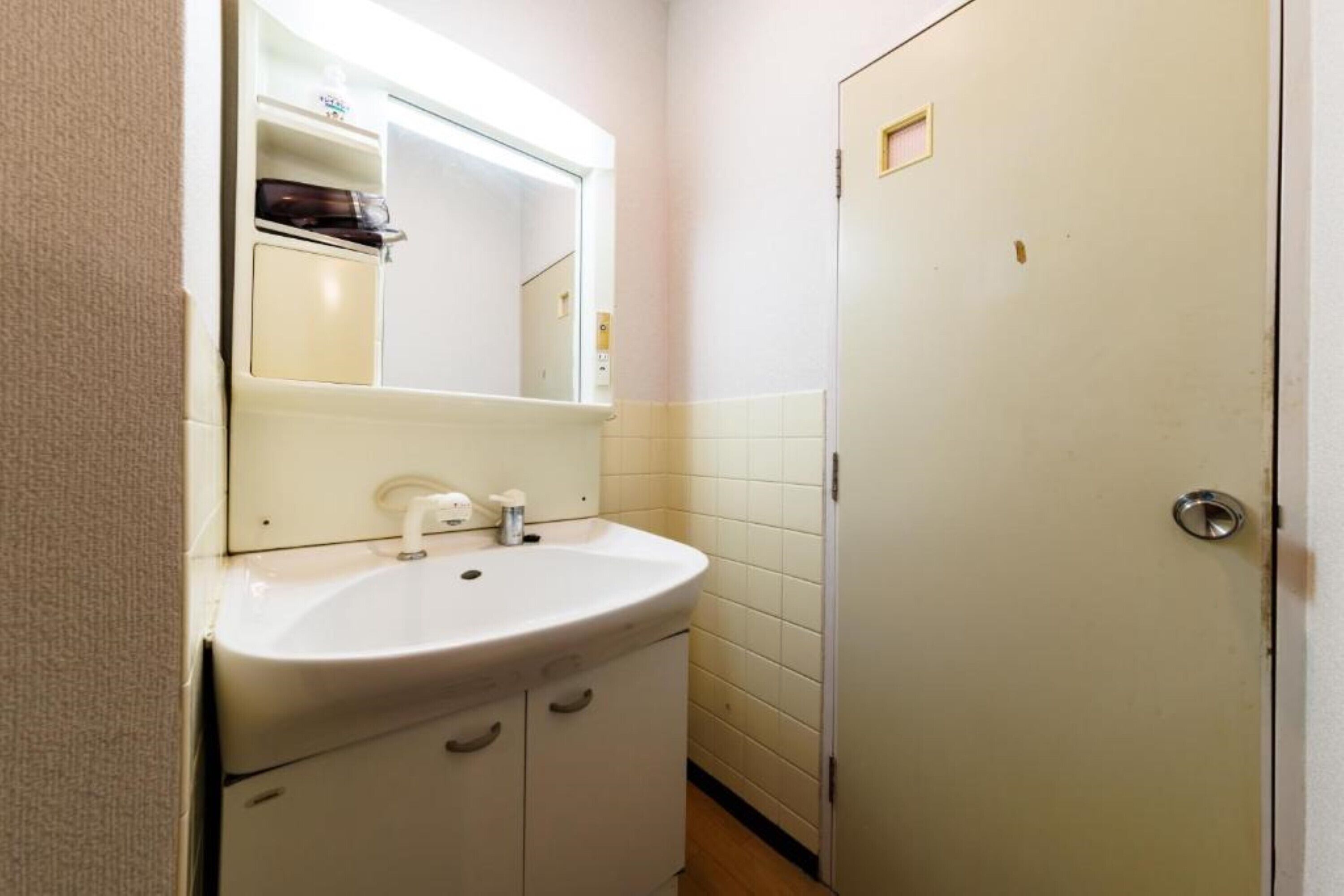 A small bathroom with a white sink, a mirror, and a door.