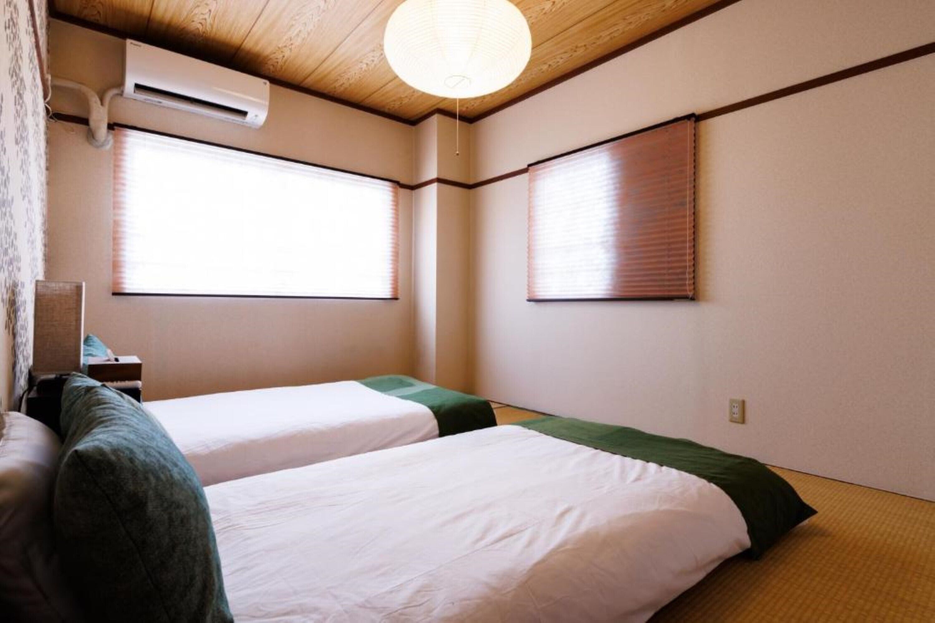 A hotel room with two beds, a ceiling fan, and an air conditioning unit.