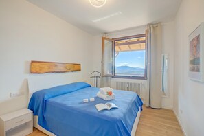 Ein Schlafzimmer mit einem Bett, einem Nachttisch, einem Fenster mit Blick und einem Bild an der Wand.