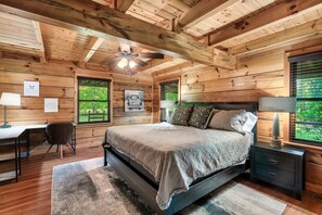 Een houten slaapkamer met een bed, bureau, stoel en nachtkastje.