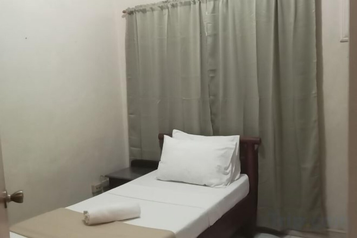 Cama de solteiro com colchão e travesseiro brancos, cabeceira de madeira e janela com cortinas.