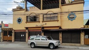 A two-story building with a beige facade, a balcony on the upper floor, and a parked car in front. - Reddoorz @ Casa Marabella Villamonte Bacolod City (Bacolod)