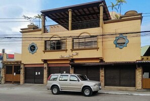 A two-story building with a beige facade, a balcony on the upper floor, and a parked car in front. - Reddoorz @ Casa Marabella Villamonte Bacolod City (Bacolod)