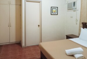 A hotel room with a bed, a wardrobe, a door, an air conditioning unit, and a small framed picture on the wall. - Reddoorz @ Casa Marabella Villamonte Bacolod City (Bacolod)