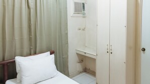 Ein Schlafzimmer mit Bett, Kleiderschrank und einem Fenster mit Jalousien.