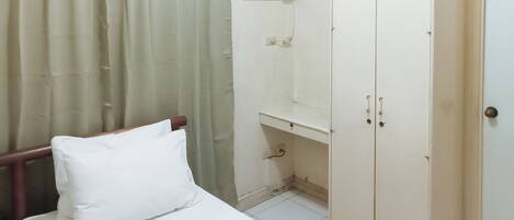 A bedroom with a bed, a wardrobe, and a window with blinds.