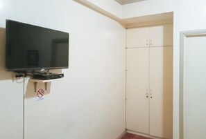 A room with a mounted television, a wardrobe, and a door. - Reddoorz @ Casa Marabella Villamonte Bacolod City (Bacolod)