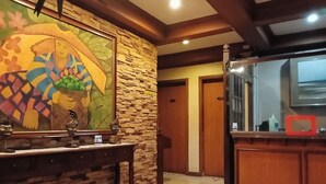 A room with a stone wall, a wooden counter, and a large mirror. There is a door leading to another room. - Reddoorz @ Casa Marabella Villamonte Bacolod City (Bacolod)