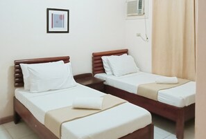 Two single beds with wooden headboards, white bedding, and a small framed picture on the wall. - Reddoorz @ Casa Marabella Villamonte Bacolod City (Bacolod)