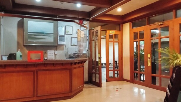 A reception area with a wooden counter, a mounted television, and framed certificates on the wall. - Reddoorz @ Casa Marabella Villamonte Bacolod City (Bacolod)
