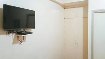 Una habitación con televisión instalada, un armario y una puerta.