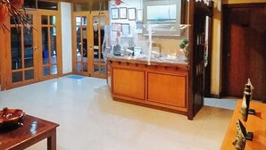 A hotel lobby with a reception desk, wooden cabinets, and a tiled floor. - Reddoorz @ Casa Marabella Villamonte Bacolod City (Bacolod)