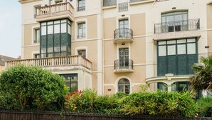 Un edificio de varios pisos con balcones, ventanas amplias y fachada color beige.