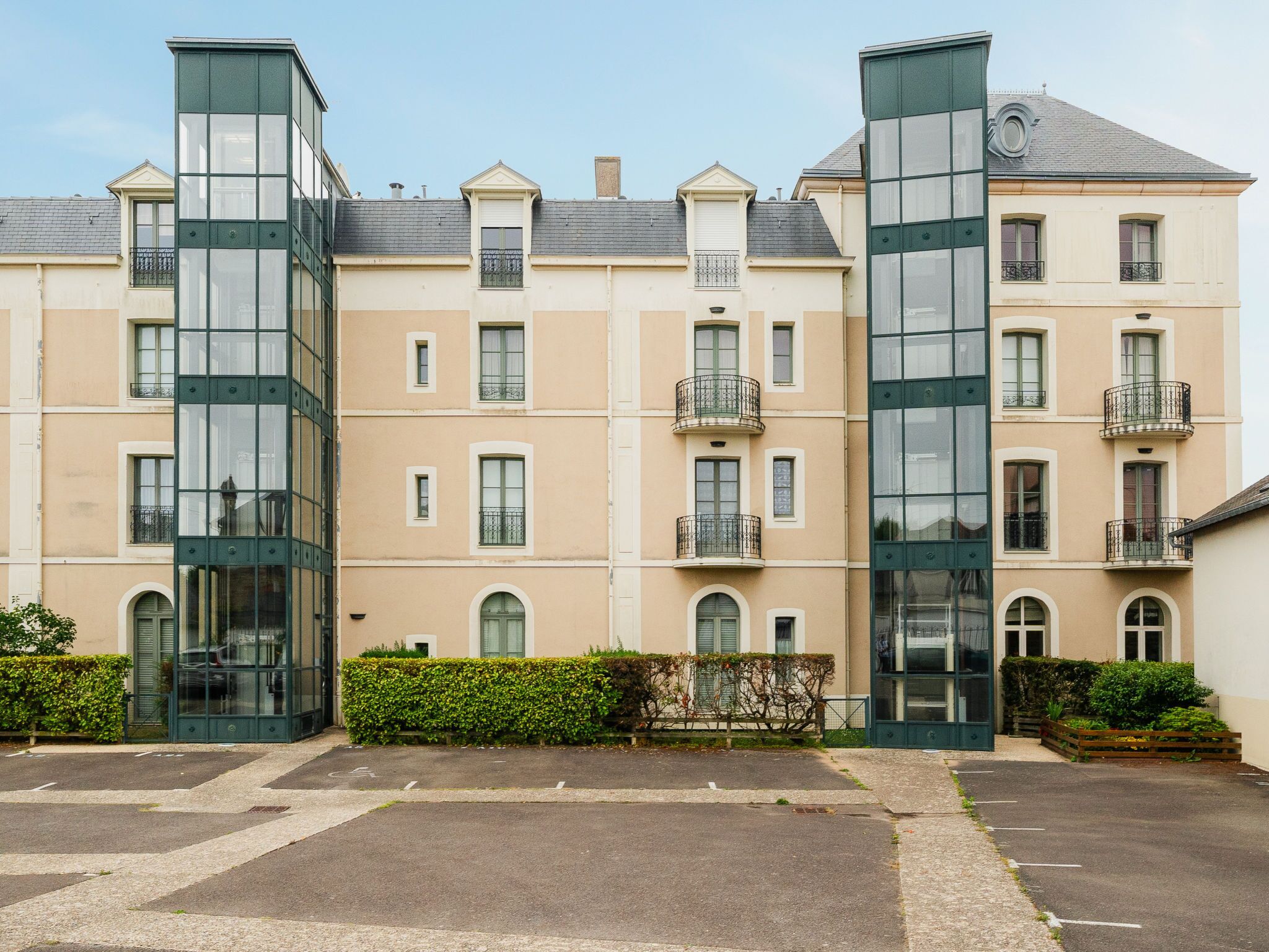 Ein mehrstöckiges Gebäude mit großen Glasfenstern, einem flachen Dach und einer symmetrischen Fassade.
