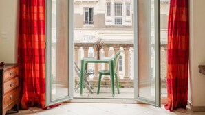Una habitación con un ventanal grande, una silla verde y una pequeña mesa.