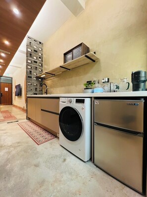 A compact kitchen with a built-in washer and refrigerator, a wooden ceiling, and a small window. - nan hai home (Tainan)