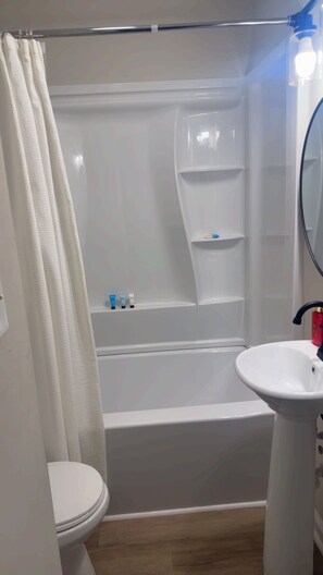 Un baño con inodoro, lavamanos, bañera y ducha.