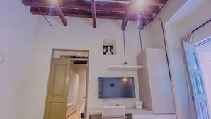 A compact room with a desk, a television, a small shelf, and a door leading to another room. - Cozy 1-bedroom suite in amazing Puebla with King size bed, WiFi and bathtub (Heroica Puebla de Zaragoza)