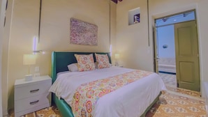 A bedroom with a bed, nightstand, and a door leading to another room. - Cozy 1-bedroom suite in amazing Puebla with King size bed, WiFi and bathtub (Heroica Puebla de Zaragoza)