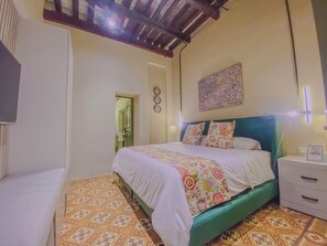 A bedroom with a bed, a nightstand, a mirror, and a door leading to a bathroom. - Cozy 1-bedroom suite in amazing Puebla with King size bed, WiFi and bathtub (Heroica Puebla de Zaragoza)