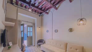 A modern living room with a sofa, a small table, and a chair. There is a door leading to an outdoor area. - Cozy 1-bedroom suite in amazing Puebla with King size bed, WiFi and bathtub (Heroica Puebla de Zaragoza)