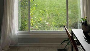 Ein Zimmer mit großem Fenster und Blick auf einen Garten.
