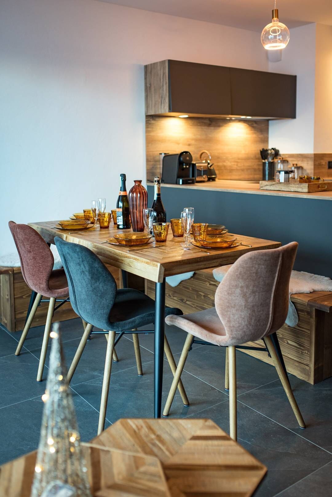 Un comedor moderno con una mesa de madera preparada para cuatro personas, rodeada de sillas tapizadas.