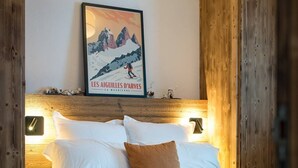 Ein ordentlich bezogenes Bett mit weißer und brauner Bettwäsche, ein gerahmtes Bild darüber und Holzvertäfelung an den Wänden.