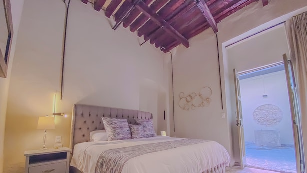 A bedroom with a bed, nightstand, and wall decor. - Enchanting suite with WiFi, King size-bed in Puebla. excellent location. (Heroica Puebla de Zaragoza)